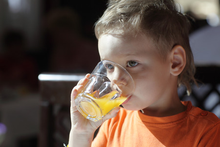Child drinking orange juice in the morningの写真素材