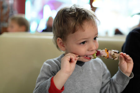 Boy is eating kebab in the restaurantの写真素材