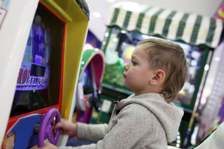 Child playing with car simulator in the amusement parkの写真素材