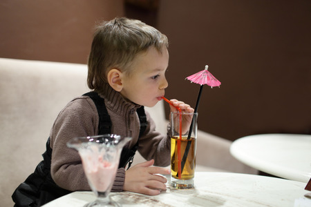 Child drinking apple juice in the cafeの写真素材