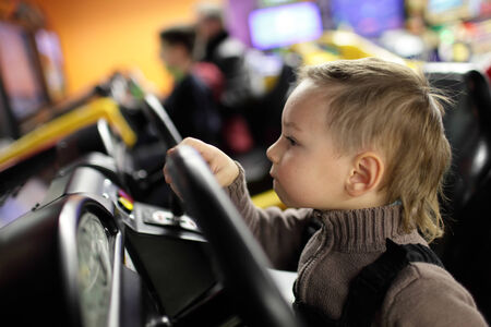 Kid playing with car simulator in the amusement parkの写真素材