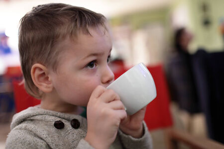 The kid drinks tea in a cafeの写真素材