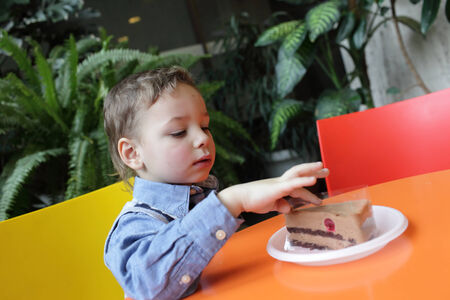 Child touching a piece of cake in the cafe