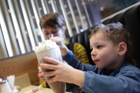 Child eats foam of milkshake in the restaurantの写真素材