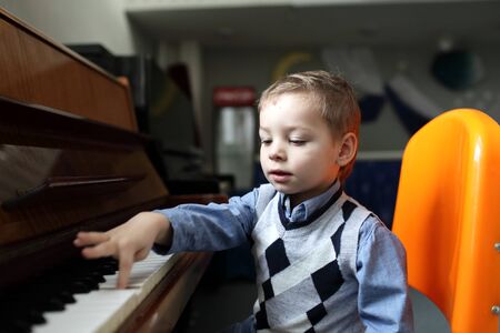 Child learning to play the piano at a classroomの写真素材