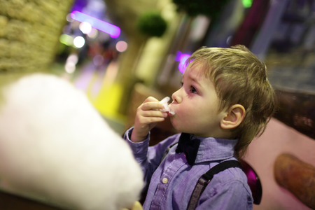 Child eating cotton candy in the cafeの写真素材