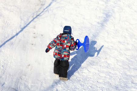 Kid climbing on a snowy hill in winter