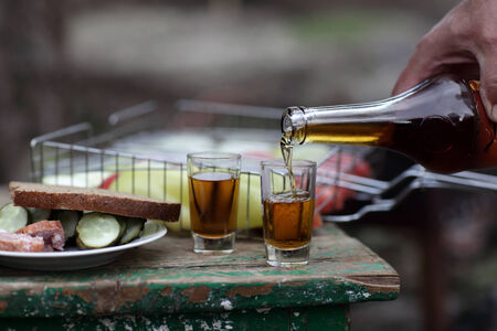 Person pouring brandy into glasses at picnicの写真素材