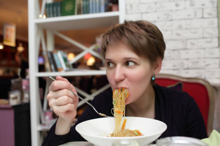 Hungry woman eating noodles in the restaurantの写真素材