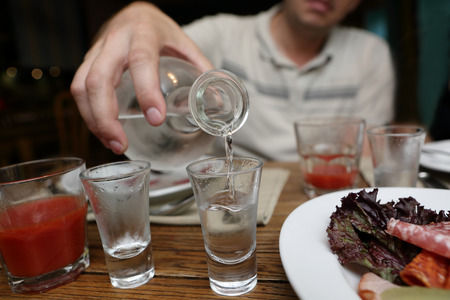 Man pouring vodka from a carafe in the pubの写真素材
