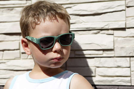 Boy with sunglasses on a wall backgroundの写真素材