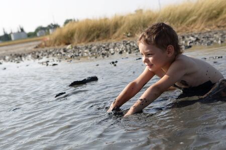 Child applying healthy mud in Primorsko-Akhtarsk, Russia