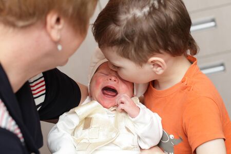 Newborn crying on his grandmother hand at homeの写真素材