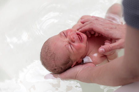 Newborn baby crying in the bath at home