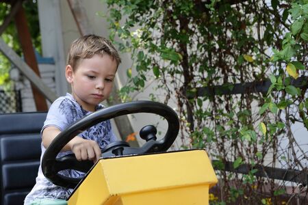 Serious kid driving a tractor at the farmの写真素材