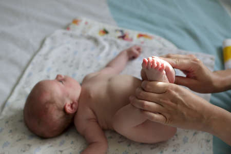 Newborn boy doing exercises on a bed at homeの写真素材