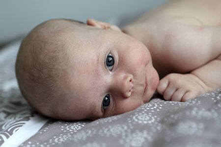 Portrait of a pensive baby boy on a bedの写真素材