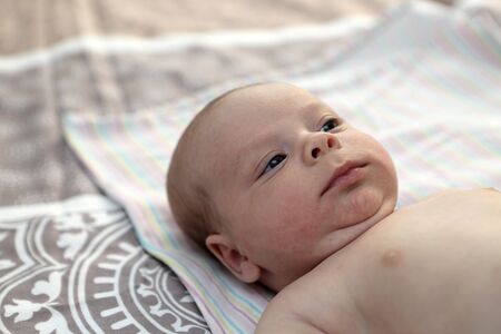 Portrait of a thinking baby on a bedの写真素材