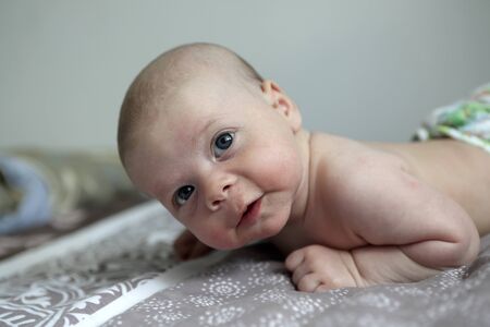 Portrait of a pensive newborn baby boy on a bed