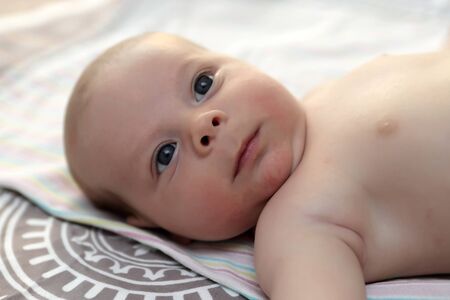 Portrait of a thinking baby boy on a bedの写真素材