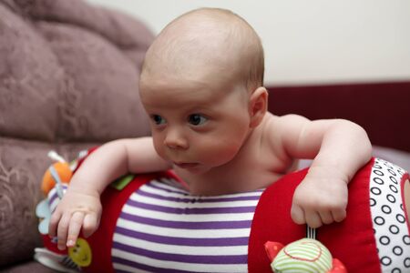 Newborn baby boy lying on a crawling roll at home