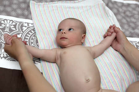 Baby doing exercise on the bed at homeの写真素材