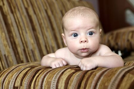 Portrait of a serious baby boy on the sofa