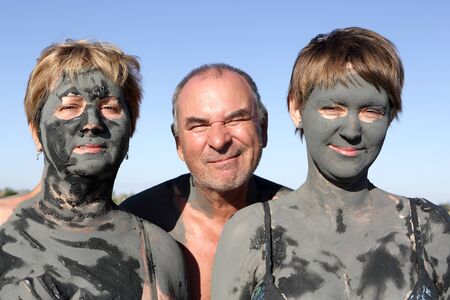 Two women covered mud and man on the sky backgroundの写真素材