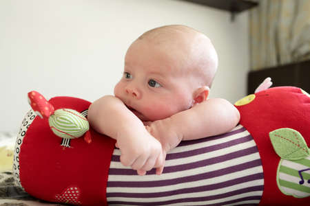 Thinking baby boy lying on a crawling roll at home