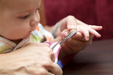 Mother tonsured nails of her son at homeの写真素材
