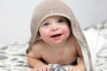 Portrait of smiling baby under bath towelの写真素材