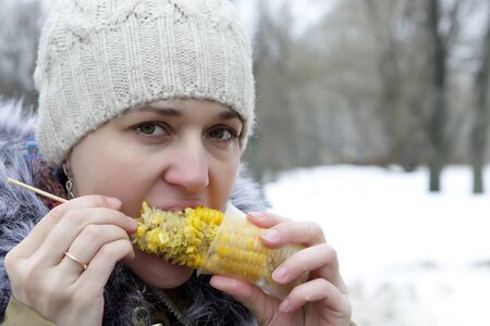 Woman eating corn in the spring parkの写真素材