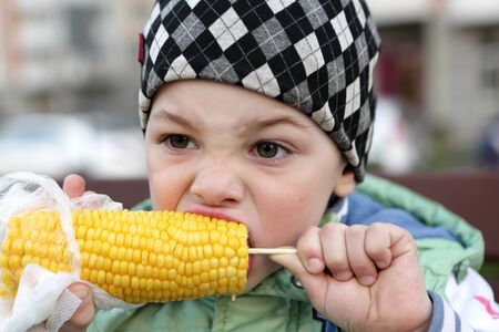 Child eating corn in the park in spring