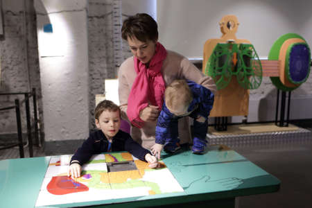 Mother and her sons playing with puzzle in a museum