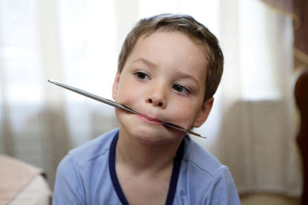 Child holding a knife in his mouthの写真素材