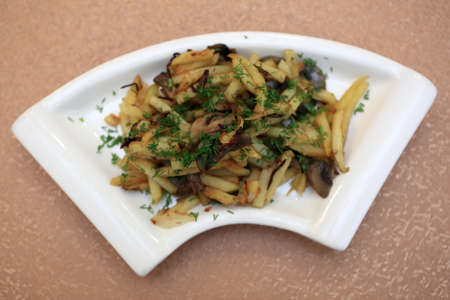 Fried potatoes with mushrooms on a plateの写真素材