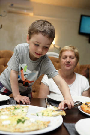 Grandmother and her grandson eating pizza in a restaurantの写真素材