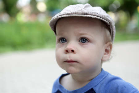 Portrait of a serious child in cap in summer parkの写真素材