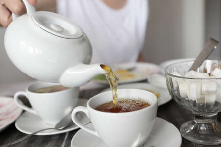 Person pouring tea in cafe in the morningの写真素材