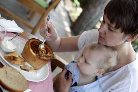 Mother with her son eating kuban borsch in a restaurantの写真素材
