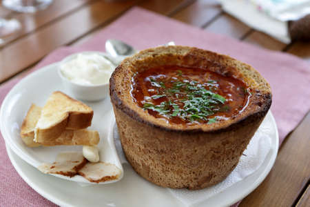 Plate with Kuban borsch in bread on a table in cafe
