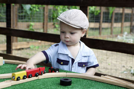 Toddler playing with toy railroad in parkの写真素材