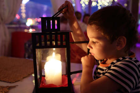 Kid looking at candle in a cafeの写真素材
