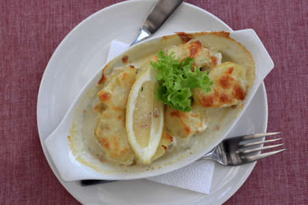 Plate with baked parmesan perch on a tableの写真素材