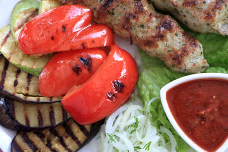 Kebab with grilled vegetables on a plate in restaurantの写真素材