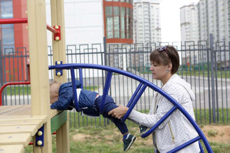 Mother holding toddler legs at a playgroundの写真素材