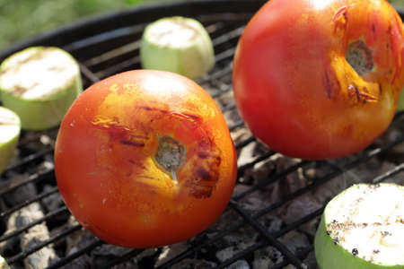 Tomatoes and zucchini on grill grate on picnicの写真素材