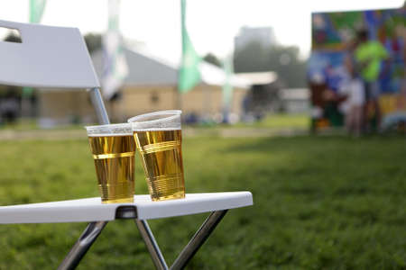 Two plastic glasses of beer on chair in parkの写真素材