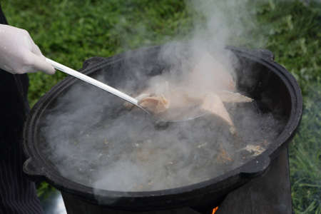 Cooking fish soup in cauldron at picnicの写真素材