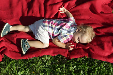 Child sleeping on rug in a parkの写真素材